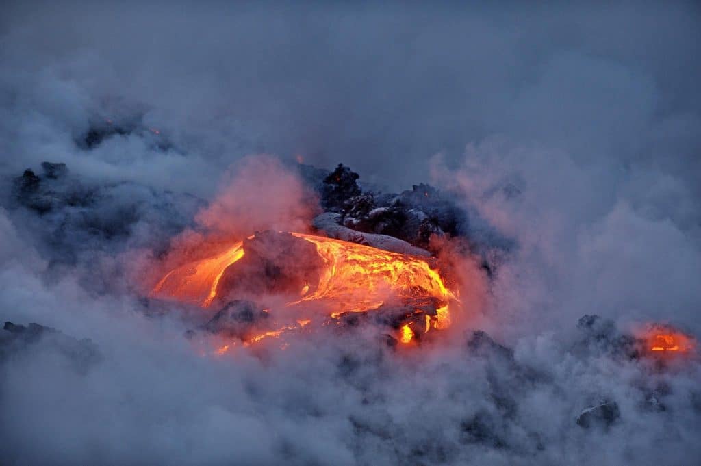 Lava stroomt door rotsen en stoom op Big Island, Hawaii