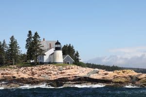 Witte vuurtoren op rotsachtige kust met dennenbomen in Maine