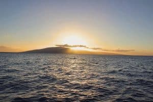 Zonsondergang boven eiland Lanai vanaf oceaan bij Maui, Hawaii