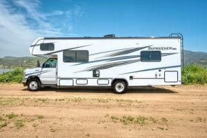 Zijaanzicht van de Mighty Class C Large camper aan een meer