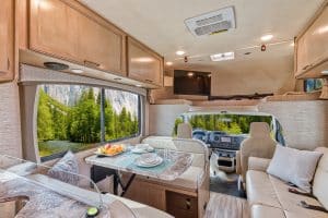 Voorzijde van het interieur met bank, tafel en bovenbed in de Mighty Class C Large