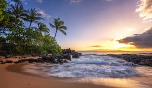 Strand met palmbomen en lavakust bij zonsondergang op Hawaii