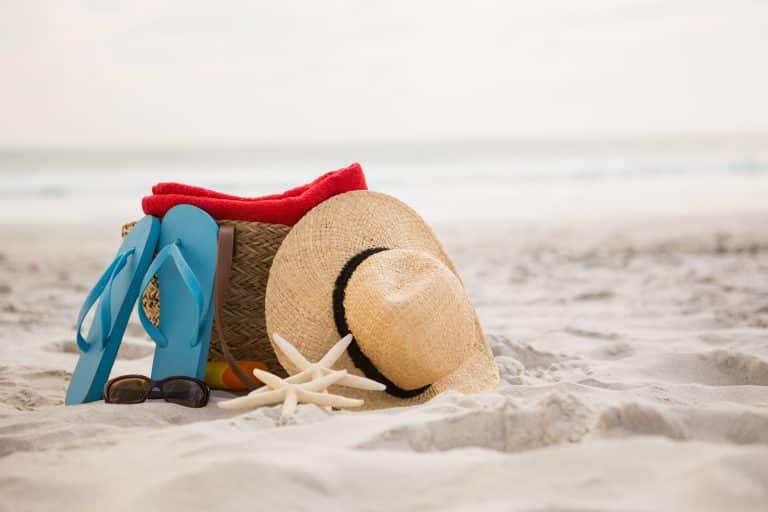 Strandtas met vakantie spullen op strand symbool voor kortlopende reisverzekering