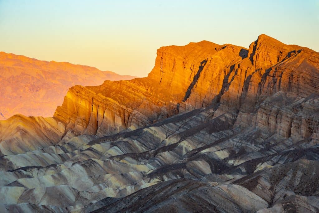 Op deze foto staat het officiële entreebord van Death Valley National Park langs de weg in een droog berglandschap. De tekst Death Valley National Park is duidelijk zichtbaar op het bord, waardoor de locatie op de afbeelding direct herkenbaar is.