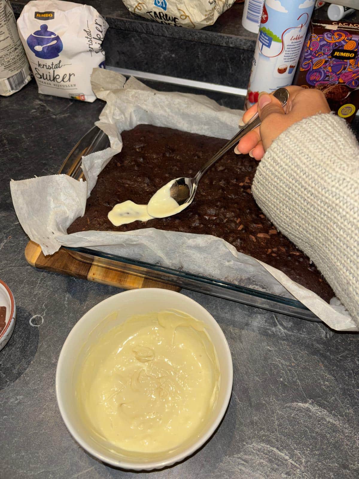 Met een lepel wordt een geestje van witte chocolade op de brownie getekend